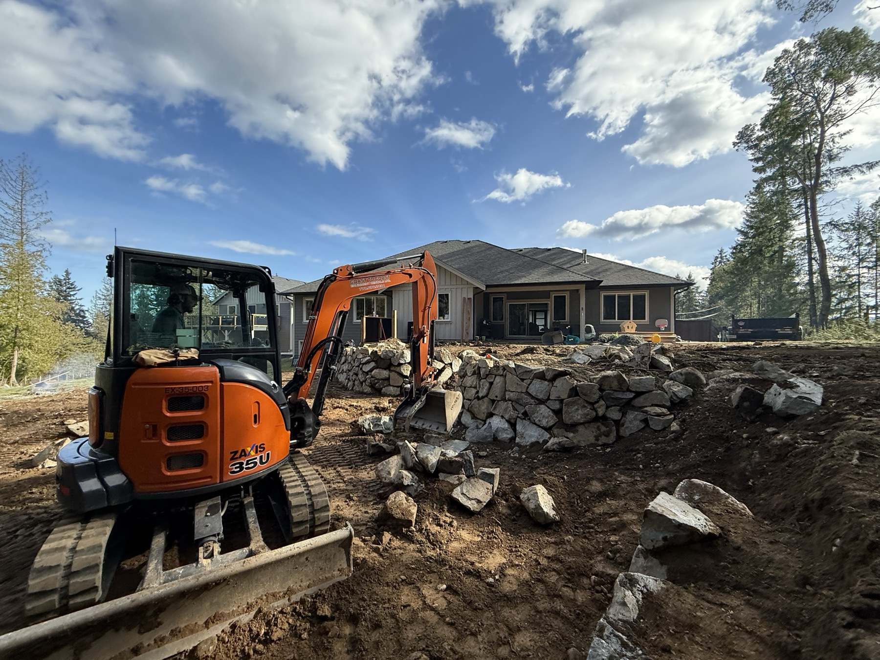 Excavator setting stone on a residential site being brought to grade