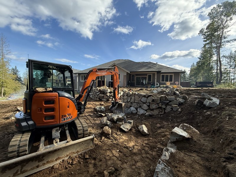 Excavator setting armour stone on a residential build