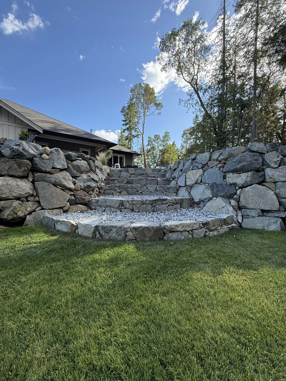 Stone stairway and terraced rock walls running up to a finished home