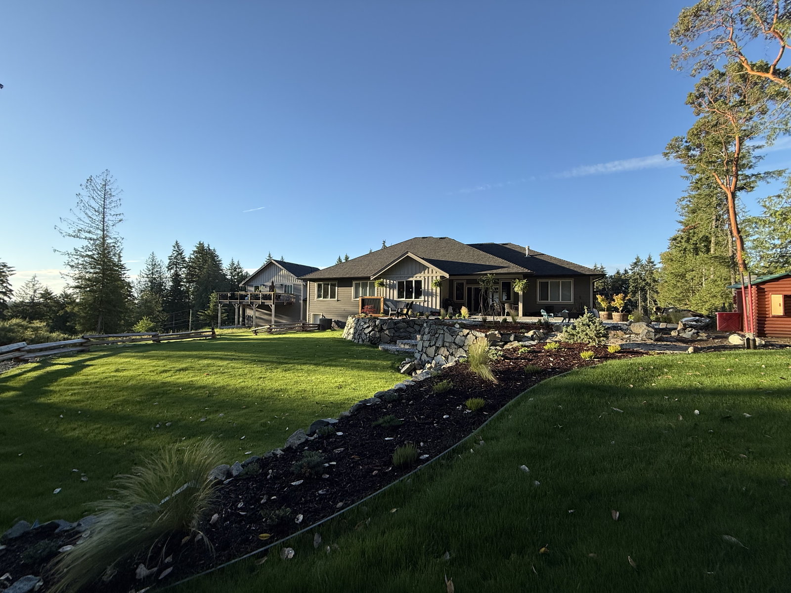 New lawn with shaped planting beds and a stone edge sweeping around a home