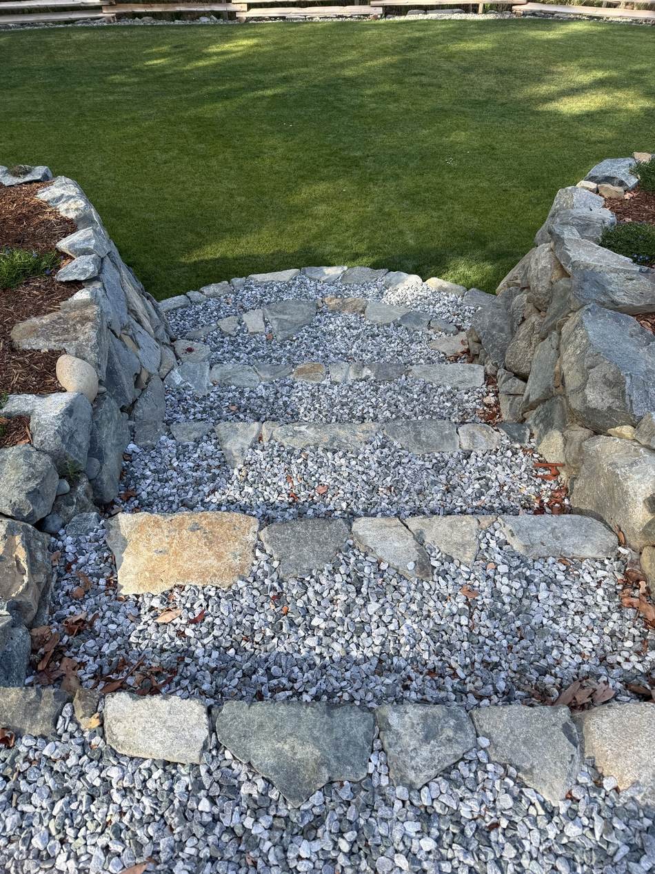 Stone steps set into a dry stacked wall with clean drainage rock