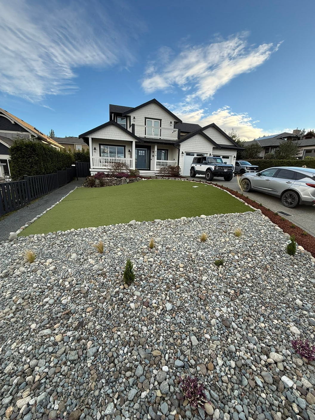 The same front yard finished with artificial turf and a river rock border